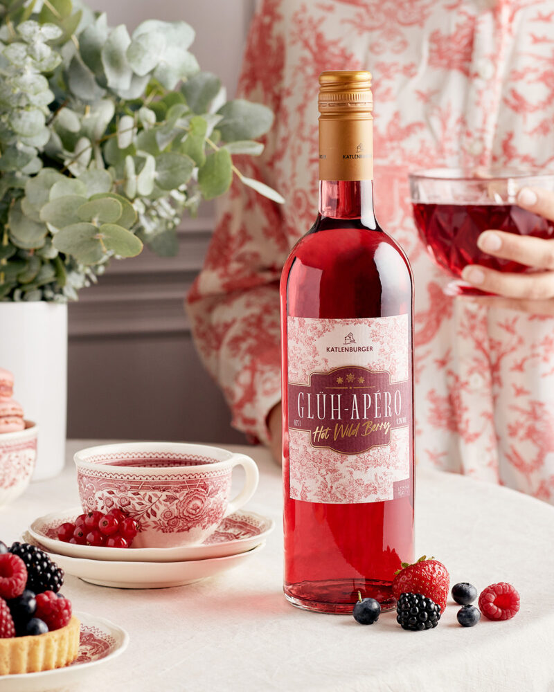 Flasche Glüh-Apero steht auf Tisch neben Beeren, Beveragefotografie